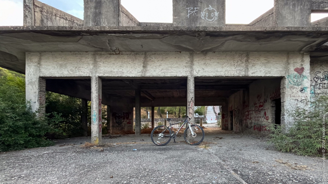 A bike, overgrown with shrubs, is in front of an unfinished hotel near the Montenegro border.