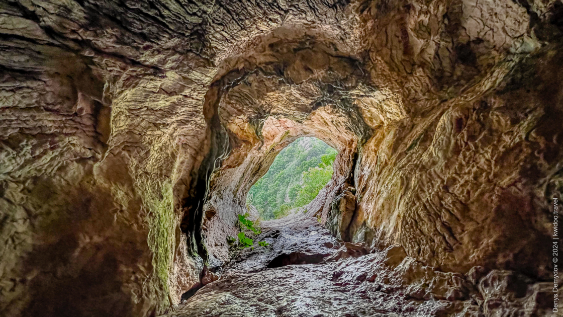 A view from inside the Ivanovici Cave to the green trees at the foot of the mountains near Bečići, Montenegro.