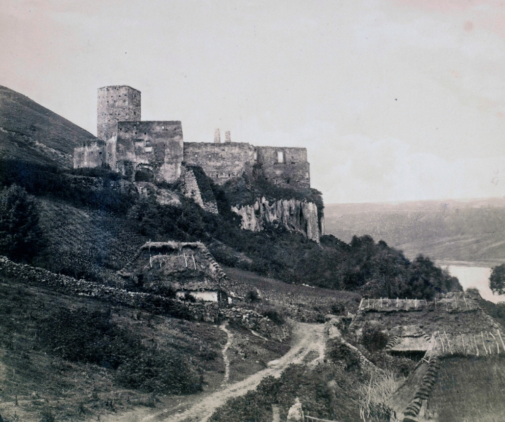 Историческое фото замка в селе Раковец. В 1880 году он был ещё более уцелевшим, стены сохранились. На переднем плане - хаты. Справа - река Днестр.